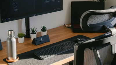 Imagem de mesa de escritório com monitor, teclado, notebook e itens de escritório.